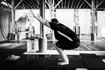 A man executes the chair pose during yoga class.