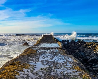 Oregon Coast - A pier jetty next to the lighthouse at a beach in Bandon