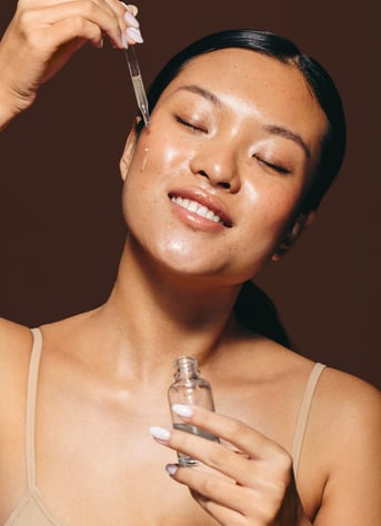 a woman with a bottle of brightening face serum in her hand
