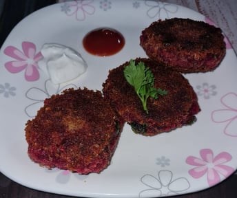 a plate with three sweet potato and beetroot  cutlets and sauce