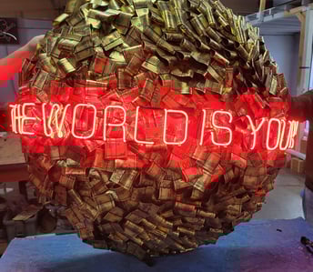 a large red neon sign that says the world is yours