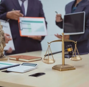 a group of people standing around a table with a laptop and a laptop