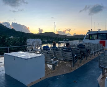 Ferry sailing at sunrise with warm golden light over calm waters in French Polynesia.