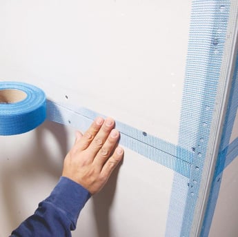 a person holding a tape tape and tape tape on a wall