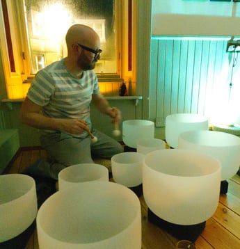 a man is sitting on a floor playing crystal bowls