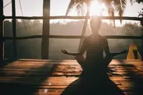 Woman practicing Pranayama breathing at sunrise.