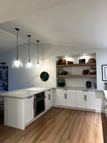 Contemporary kitchen corner with white shaker base cabinets, quartz countertops, wood shelving, and 