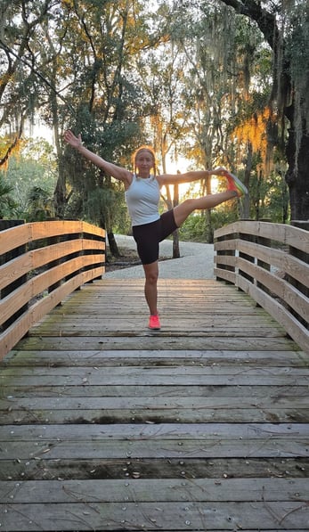 Eva practicing yoga on a wooden bridge at sunset