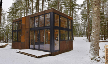 Modern prefab modular tiny home in snowy forest by builders