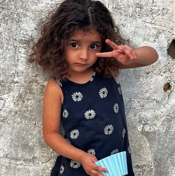 a little girl with curly hair and a blue dress