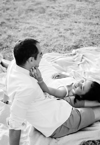 Black and white couple photo in Provence field — she rests on his legs and caresses his cheek