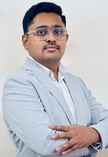 a man in a suit and glasses with a white shirt. Prajwal R Basavaraju founder of The Evolving Man
