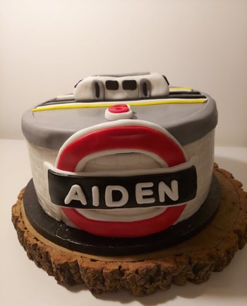 a cake with a train themed cake on top of a wooden slice