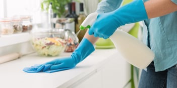 Agent de M & M Services Pro nettoyant une surface avec un spray nettoyant et des gants bleu à Rouen