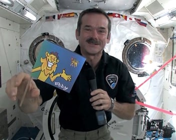 un astronaute tenant un drapeau dans la Station spatiale internationale