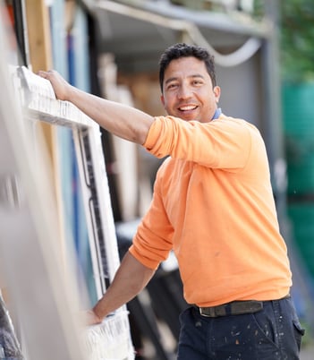 Window installer in orange shirt holding a uPVC window sill