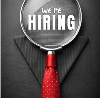 a we're hiring magnifying glass in front a black suit