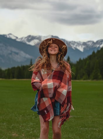 a woman in a plaidered blanket in front of a mountain in Banff