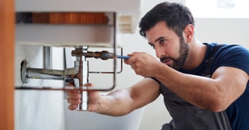 a handyman in overalls and overalls is fixing a leaky faucet