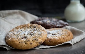 two cookies and a milkshake in a glass jar