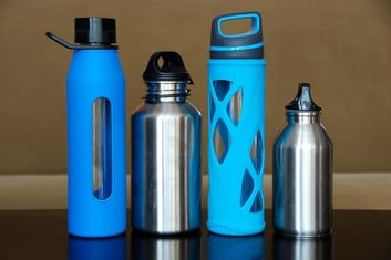 Reusable water bottles in stainless steel and BPA-free plastic with blue designs.