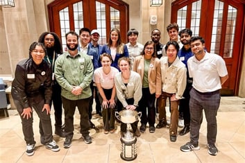 a group of skandalaris venture competition finalists standing around a trophy