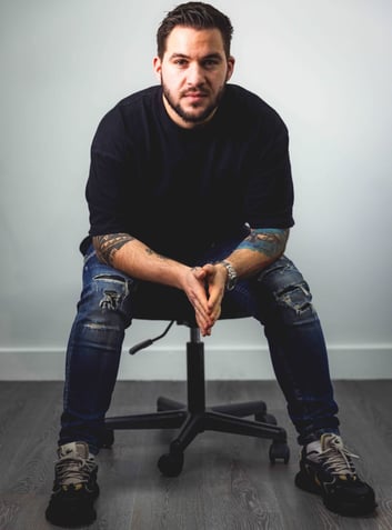 a man sitting on a chair with his hands on his knees