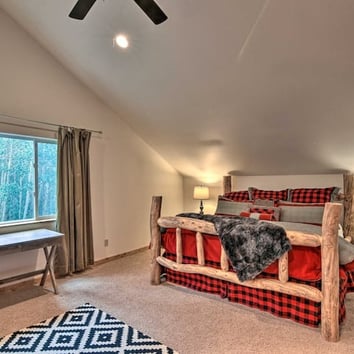 Rustic bedroom with log-frame bed, plaid bedding, and vaulted ceiling.