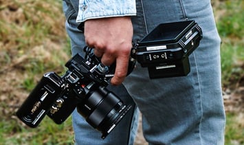 Mann in blauer Jeans, draußen, mit Kamera Rig in der Hand, von hinten