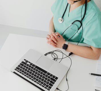 a nurse in scrub scrubs and a stethoscope on a laptop