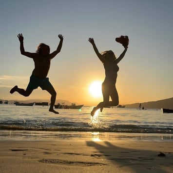 two children jumping in the air at sunset