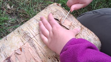 a child's hand holding a small wooden block