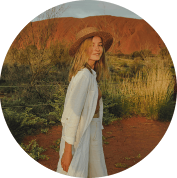 portrait of young woman in a hat standing in front of Uluru, Australia