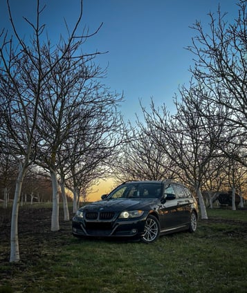 A car parked in a field with trees and a sky background