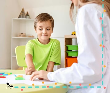 Niño participa en evaluación ADOS-2 infantil con profesional en contexto terapéutico lúdico.