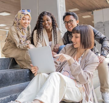 a group of people sitting on steps with a laptop