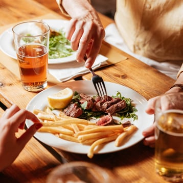 foto di un piatto di carne succulento con patatine fritte e delle birre. Scena di life style