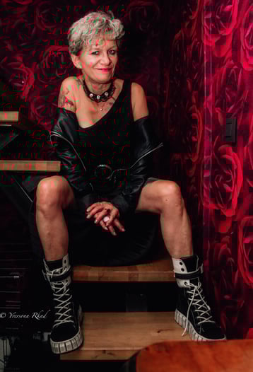 Portrait d'une femme élégante assise sur un tabouret dans un décor rouge par Yveophoto