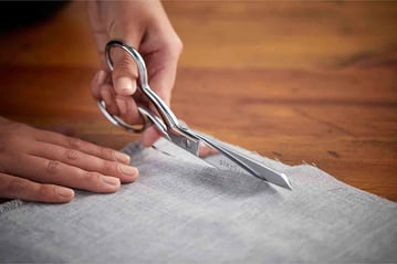 a person holding a pair of scissors and a pair of scissors