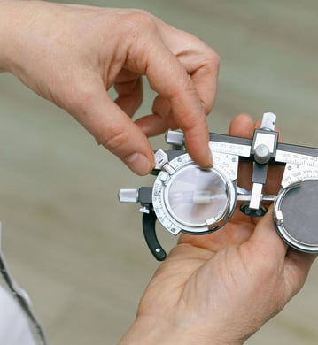 les mains d'un opticien qui règle des verres d'une lunette d'essai pour faire un examen de vue.