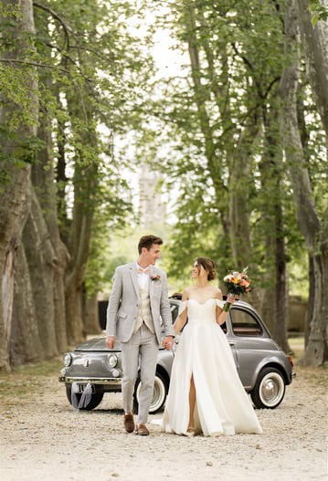Wedding couple walking under trees with vintage Fiat 500 — South of France wedding photographer cost