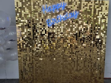 Blue happy birthday neon sign on a gold shimmer wall for Tipene's daughter in Logan.
