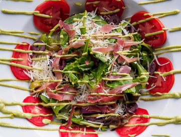 a salad with tomatoes and cheese on a white plate