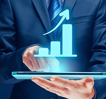 Man in a suit holds a tablet and touches the screen with an index finger as a holographic upward growth bar chart emerges.