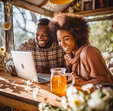 a man and woman sitting at a table with a laptop