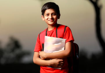 a young hindu student is holding a book and smiling