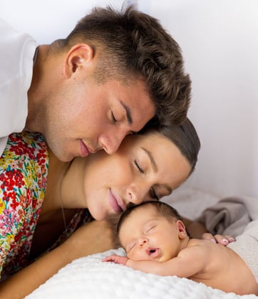 Sessió de fotos newborn a Girona amb bebè recent nascuda dormint amb els pares en estudi fotogràfic