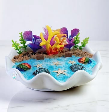 Handcrafted soy wax candle in a white shell with vibrant coral, starfish, and sea spaces decor 
