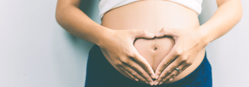 Coeur avec les mains sur le ventre d'une femme enceinte