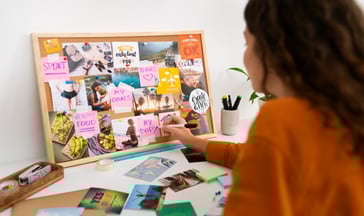 A girl is creating a vision board depicting one can achieve their goals by goal design and planning